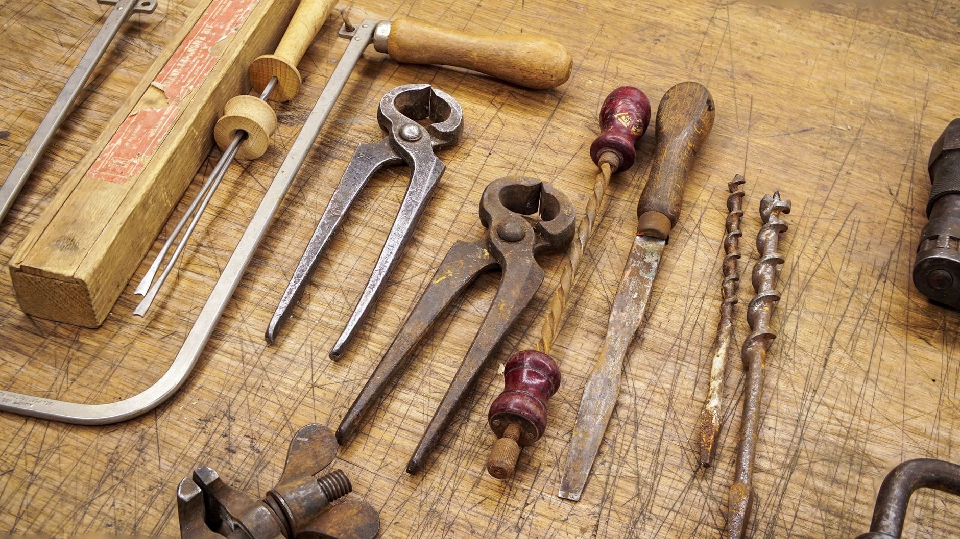 A collection of rusty vintage tools displayed on a wooden workbench, showcasing woodworking history.